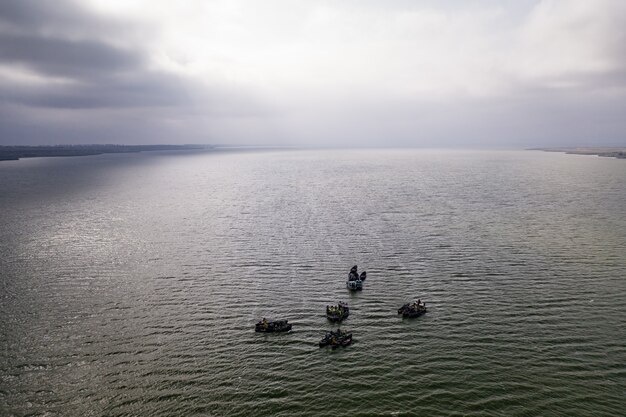 Barcos de pesca, flutuando nas águas calmas e indo pescar sob um céu de nuvens