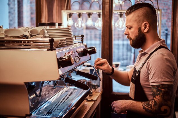 Barista bonito de uniforme fazendo café para um cliente na cafeteria