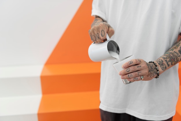 Barista masculino com tatuagens adicionando leite ao café
