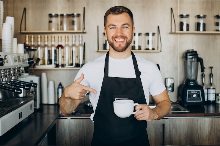 Foto grátis barista masculino em uma cafeteria segurando uma xícara ao lado do balcão
