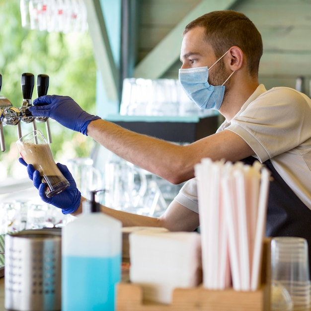 Foto grátis barista masculino no trabalho usando máscara