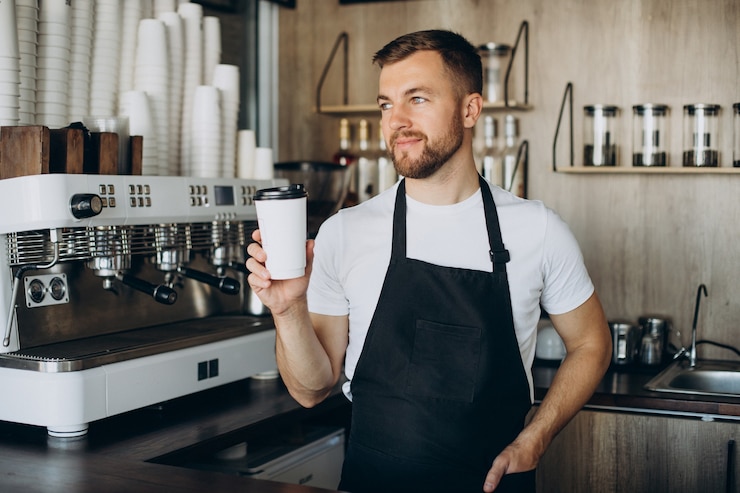 Foto grátis barista masculino segurando café em um copo de papelão
