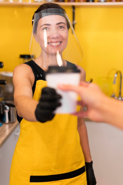 Foto grátis barista servindo com proteção facial