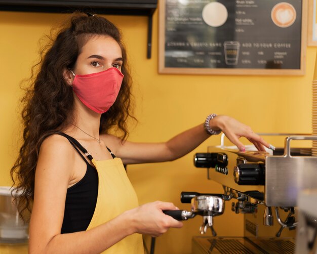 Foto grátis barista usando máscara médica enquanto faz café dentro de casa