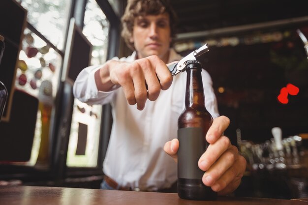 Barman, abrindo uma garrafa de cerveja