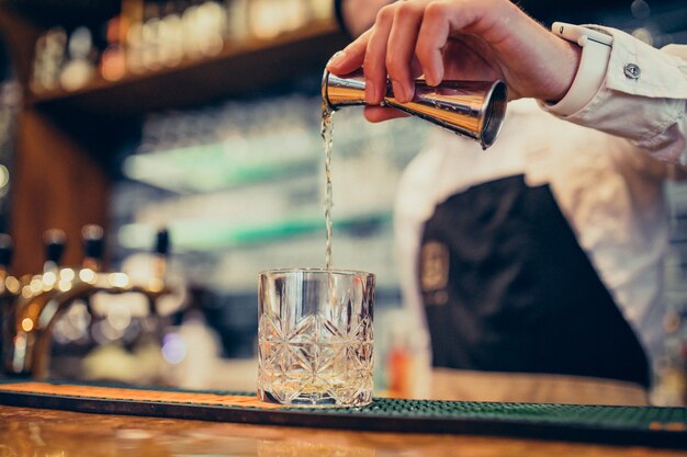 Barman bonito fazendo beber e cocktails num balcão