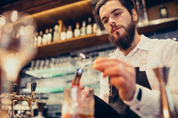 Barman bonito fazendo beber e cocktails num balcão