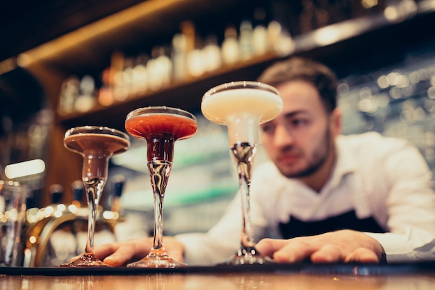 Barman bonito fazendo beber e cocktails num balcão