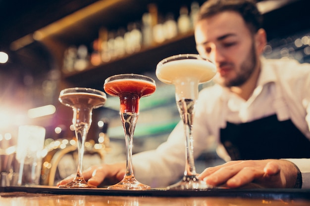 Barman bonito fazendo beber e cocktails num balcão