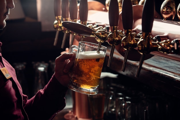 barman enche a caneca de cerveja da torneira de cerveja