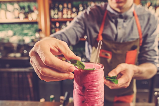 Barman especialista está fazendo um cocktail na boate.