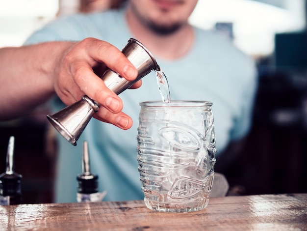 Barman irreconhecível derramando álcool em vidro