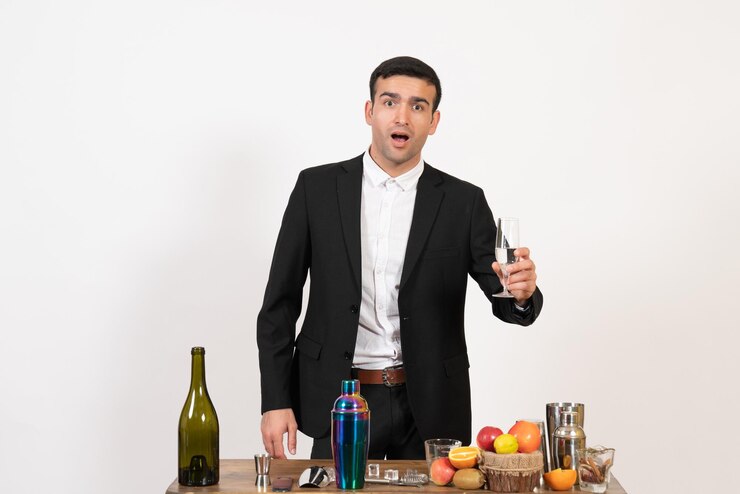 Foto grátis barman masculino de frente para a mesa com bebidas e coquetéis na parede branca bar de bebidas alcoólicas do clube noturno