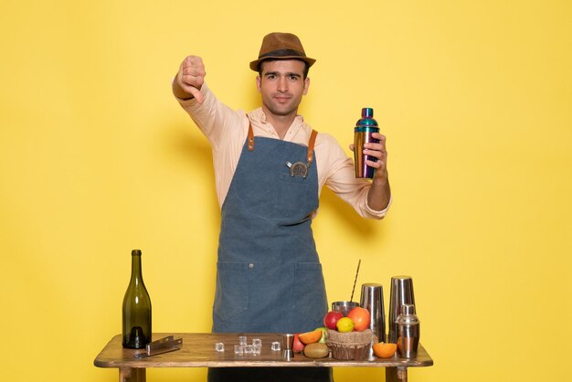 Barman masculino de frente para a mesa com bebidas e gelo no bar de bebidas masculinas de boate de parede amarela