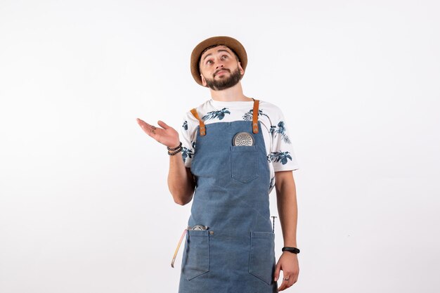 Barman masculino de frente para um bar de bebidas alcoólicas em uma parede branca clara