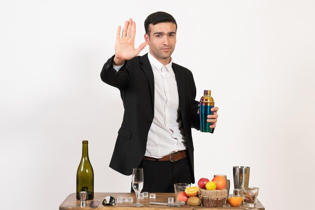 Foto grátis barman masculino de terno clássico em frente à mesa com bebidas na parede branca à noite, bar do clube masculino, bebida alcoólica