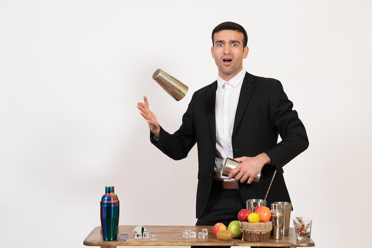 Foto grátis barman masculino de terno trabalhando com coquetéis e fazendo bebida na parede branca à noite.