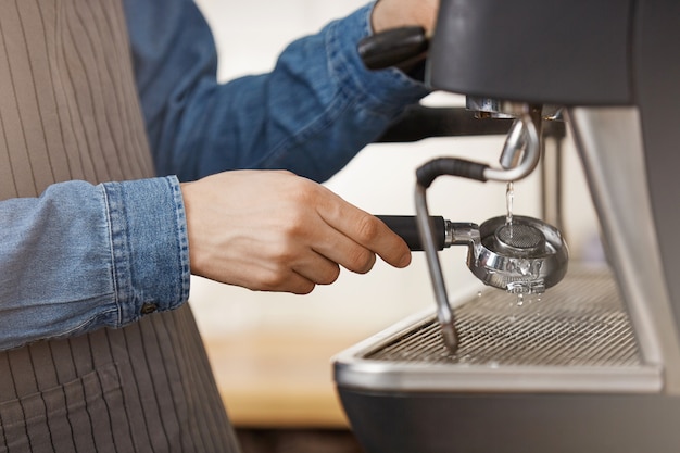 Barman masculino em camisa jeans e avental limpeza portafilter sem fundo.