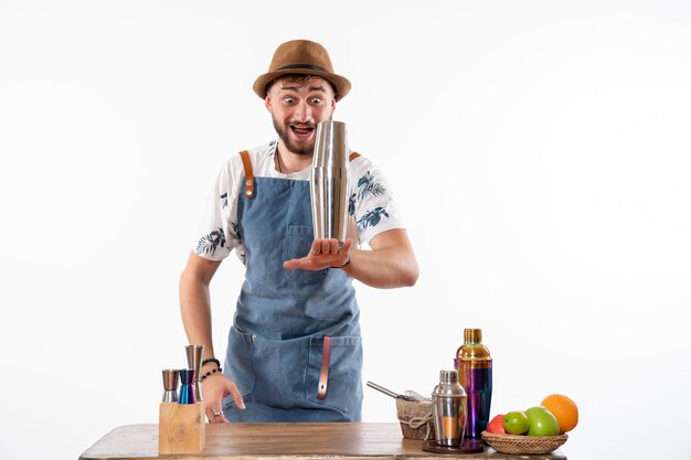 Barman masculino em frente à mesa do bar preparando uma bebida na parede branca