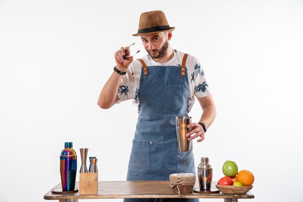 Barman masculino fazendo uma bebida em uma coqueteleira na parede branca bar de bebidas alcoólicas em bar noturno