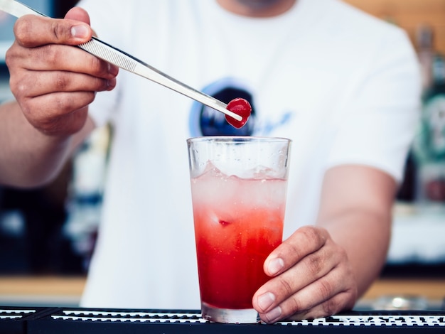 Barman masculino que decora a bebida com cereja