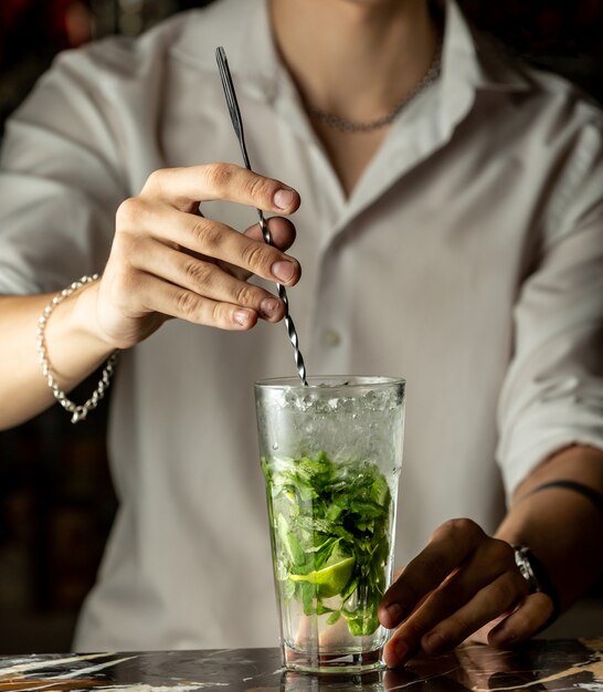 Barman mistura mojito cocktail com colher de metal