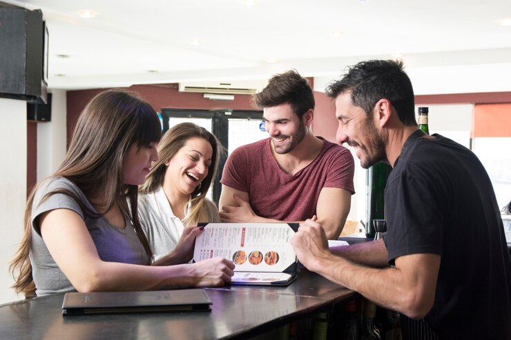 Foto grátis barman mostrando o menu para os clientes no balcão de bar