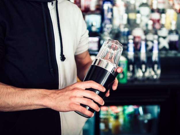 Barman novo masculino que usa o tumbler para fazer a bebida