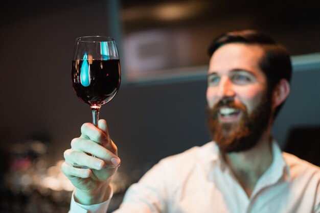 Barman, olhando para o copo de vinho tinto