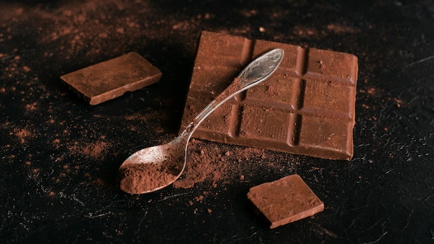 Foto grátis barra de chocolate e colher com cacau em pó