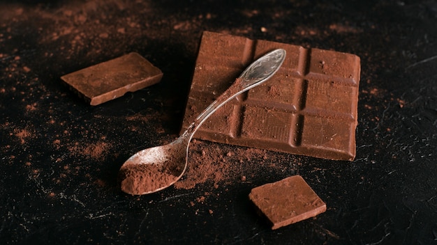 Barra de chocolate e colher com cacau em pó
