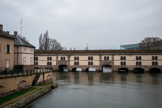 Barrage Vauban cercada por água e edifícios sob um céu nublado em Estrasburgo, na França