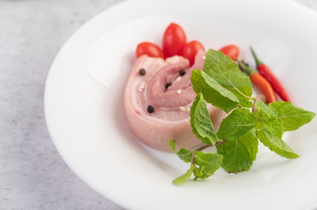 Barriga de porco em um prato branco com pimenta sementes de tomate e especiarias.