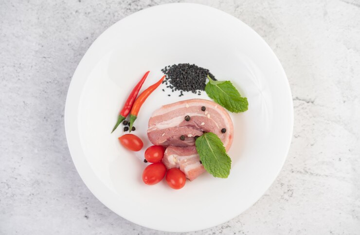 Foto grátis barriga de porco em um prato branco com pimenta sementes de tomate e especiarias.