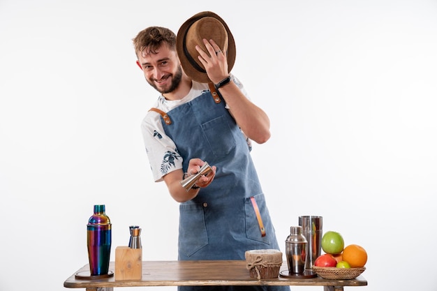 Bartender de frente para o bar, usando seu chapéu e sorrindo na parede branca, bar de bebidas alcoólicas em clube noturno