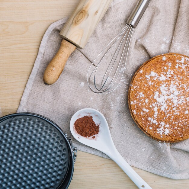 Base de bolo caseiro com chocolate em pó; rolo de massa; bata e assar recipiente na mesa