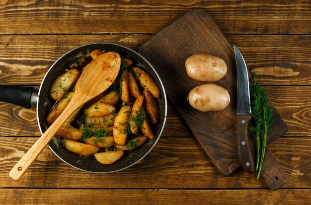 Batatas assadas em uma frigideira com batatas cruas e endro