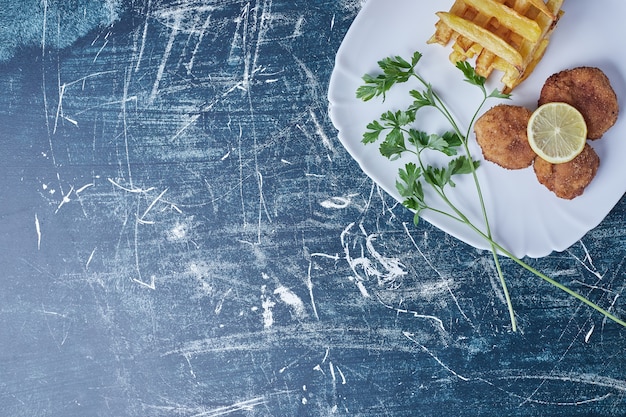 Foto grátis batatas fritas com cotlets e limão.