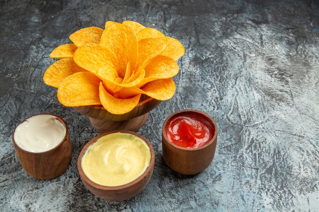 Batatas fritas crocantes decoradas com sal em forma de flor, maionese e ketchup na mesa cinza