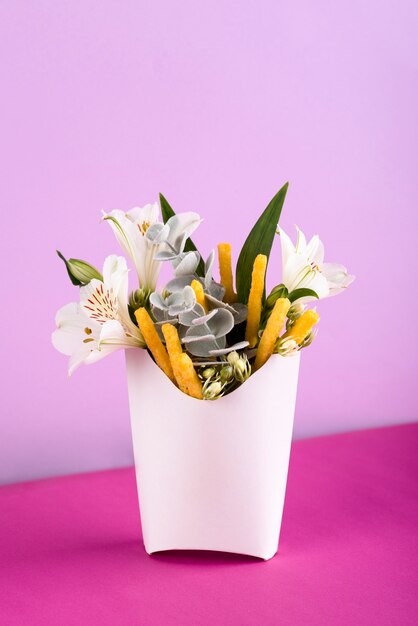 Batatas fritas de alto ângulo e flores no fundo roxo