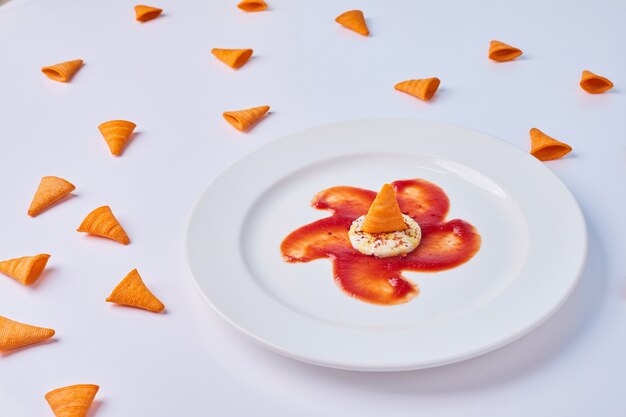 Batatas fritas de triângulo servidas com molho de tomate vermelho e biscoitos no branco.