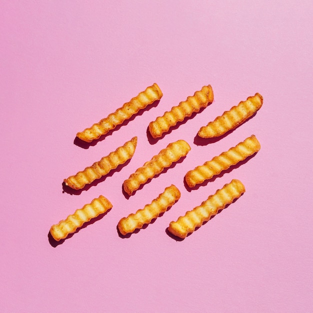 Foto grátis batatas fritas douradas no fundo rosa