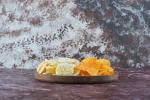 Foto grátis batatas fritas e chips de queijo no prato, na mesa de mármore.