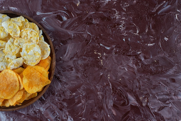 Batatas fritas e chips de queijo no prato, na mesa de mármore.