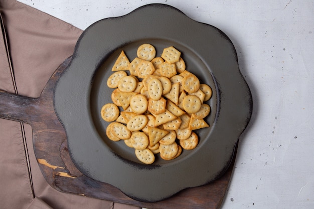 Batatas fritas salgadas de vista superior dentro de um prato escuro no fundo cinza salgadinho biscoito comida de café da manhã