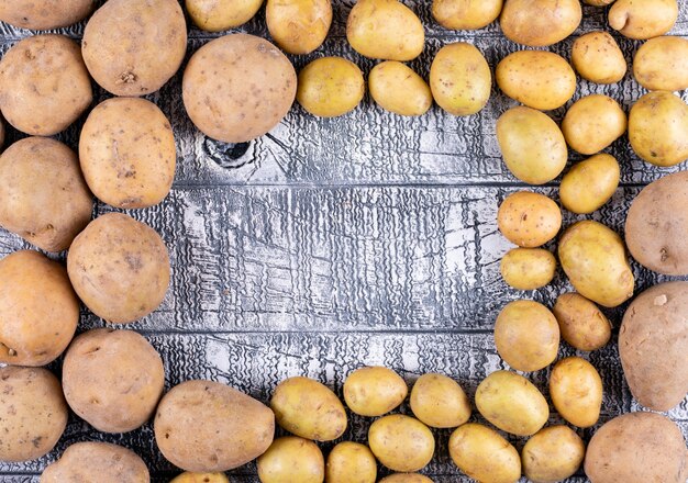 Batatas pequenas e grandes em uma mesa de madeira escura