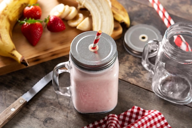 Batido de morango e banana fresco em pote na mesa de madeira