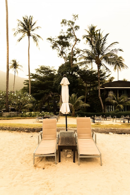 Beautiful Silhouette guarda-chuva de luxo e cadeira ao redor da piscina no resort da piscina do hotel com palmeira de coco no horário do nascer do sol - Vintage Filter and Boost up color Processing