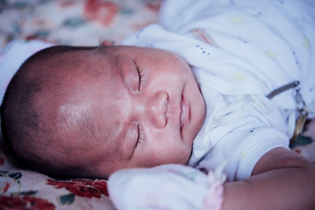 Bebê asiático dormindo na cama