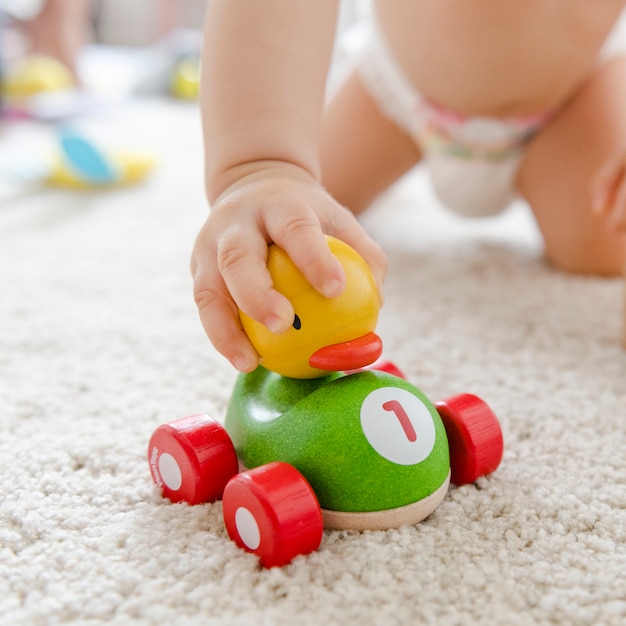Bebê brincando com um carro de madeira